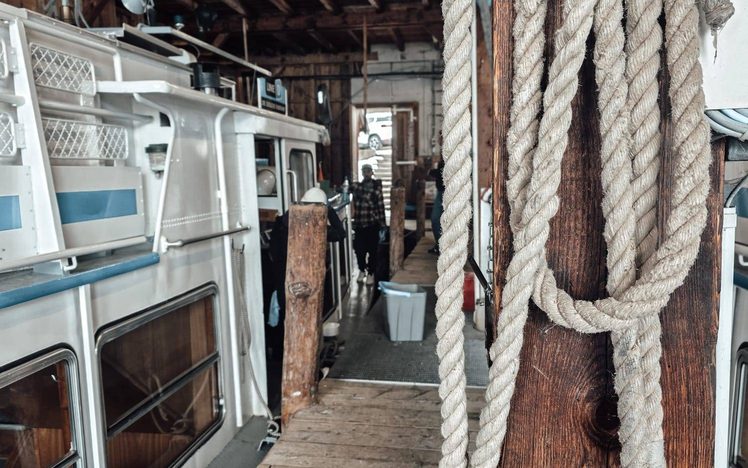 Steg im Bootshaus mit Tauen und vertäuten Ausflugsschiffen